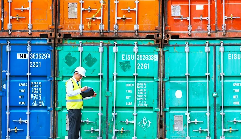Person next to shipping containers trying to answer the question of what is asset tracking?
