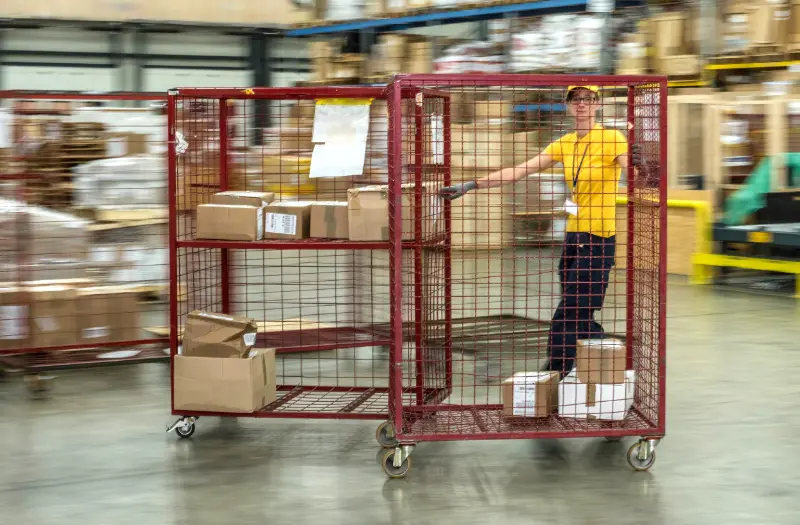 Person pushing a parcel cage that uses a parcel cage tracking solution.