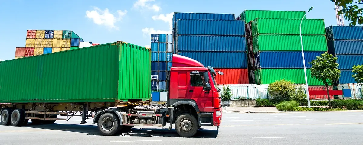 Truck in front of shipping containers that use a solution to track and trace in logistics